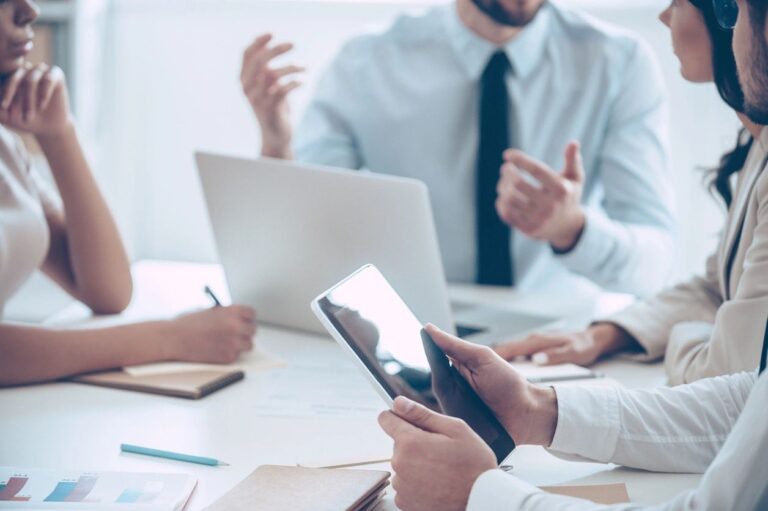 Four professionals in a meeting reviewing a website compliance audit on a laptop